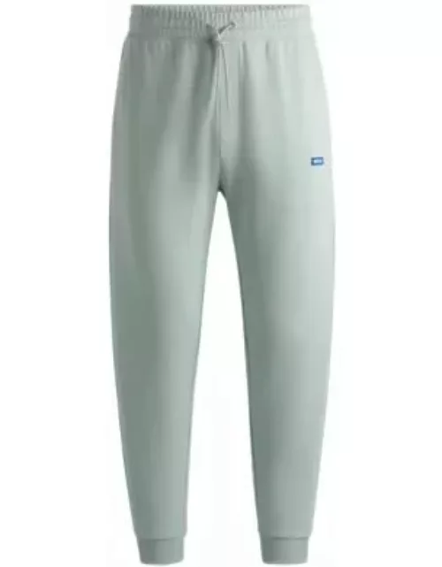 Cotton-terry tracksuit bottoms with blue logo patch- Light Green Men's Jogging Pant